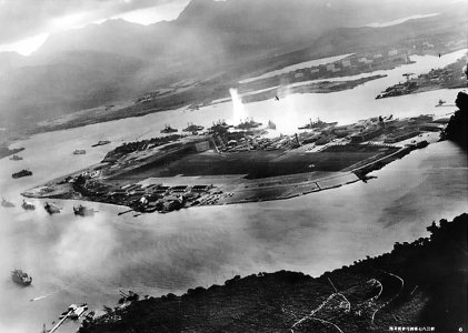Foto van Pearl Harbor vanuit een Japans vliegtuig. In het midden is te zien hoe de eerste bommen vallen. In het midden en uiterst rechts zijn Japanse vliegtuigen te zien. Imperial Japanese Navy / Public domain via Wikimedia Commons Aanval op Pearl Harbor